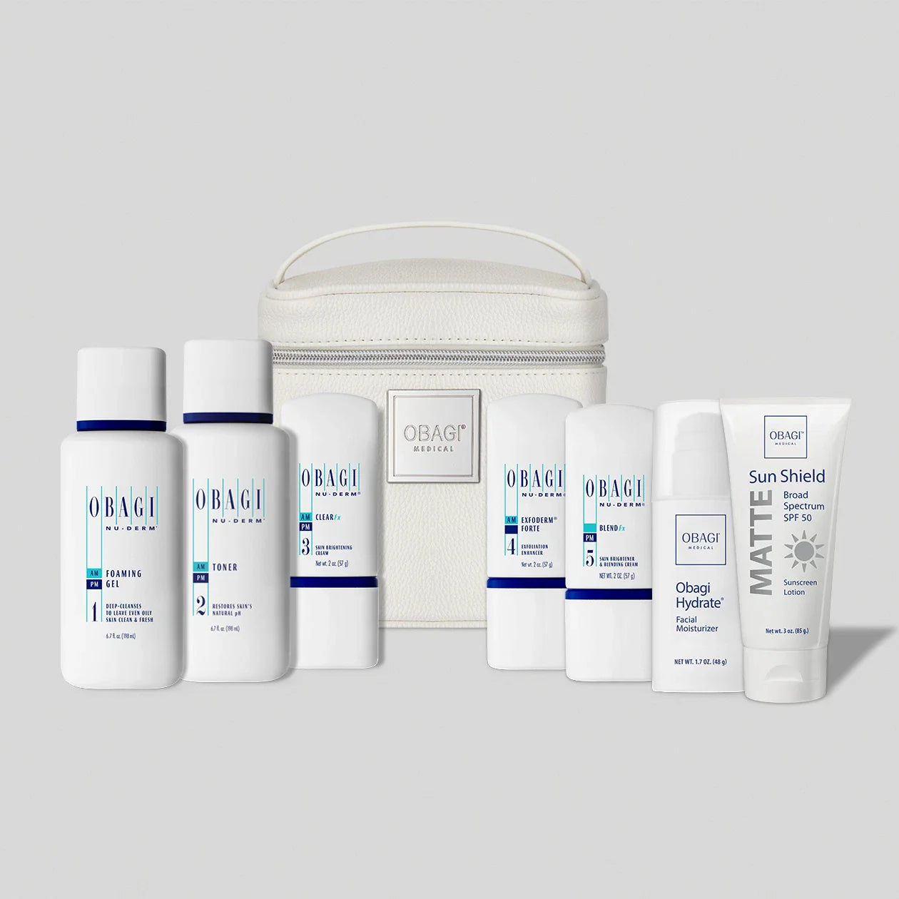 Obagi Nu-Derm Fx System Oily skincare bundle products including bottles and a cream with a white bag on a light gray background.