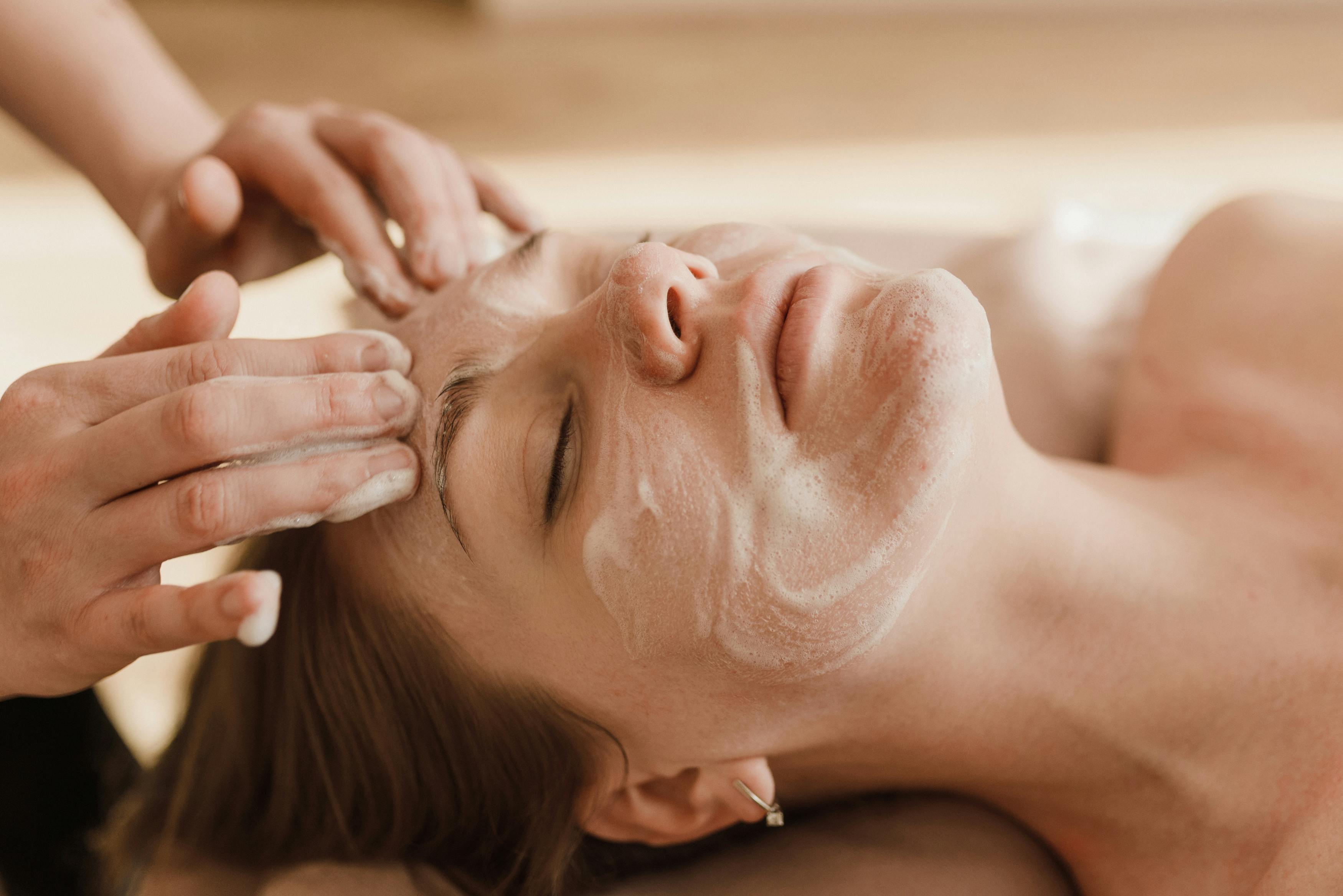 Person receiving a facial massage with cream on their face