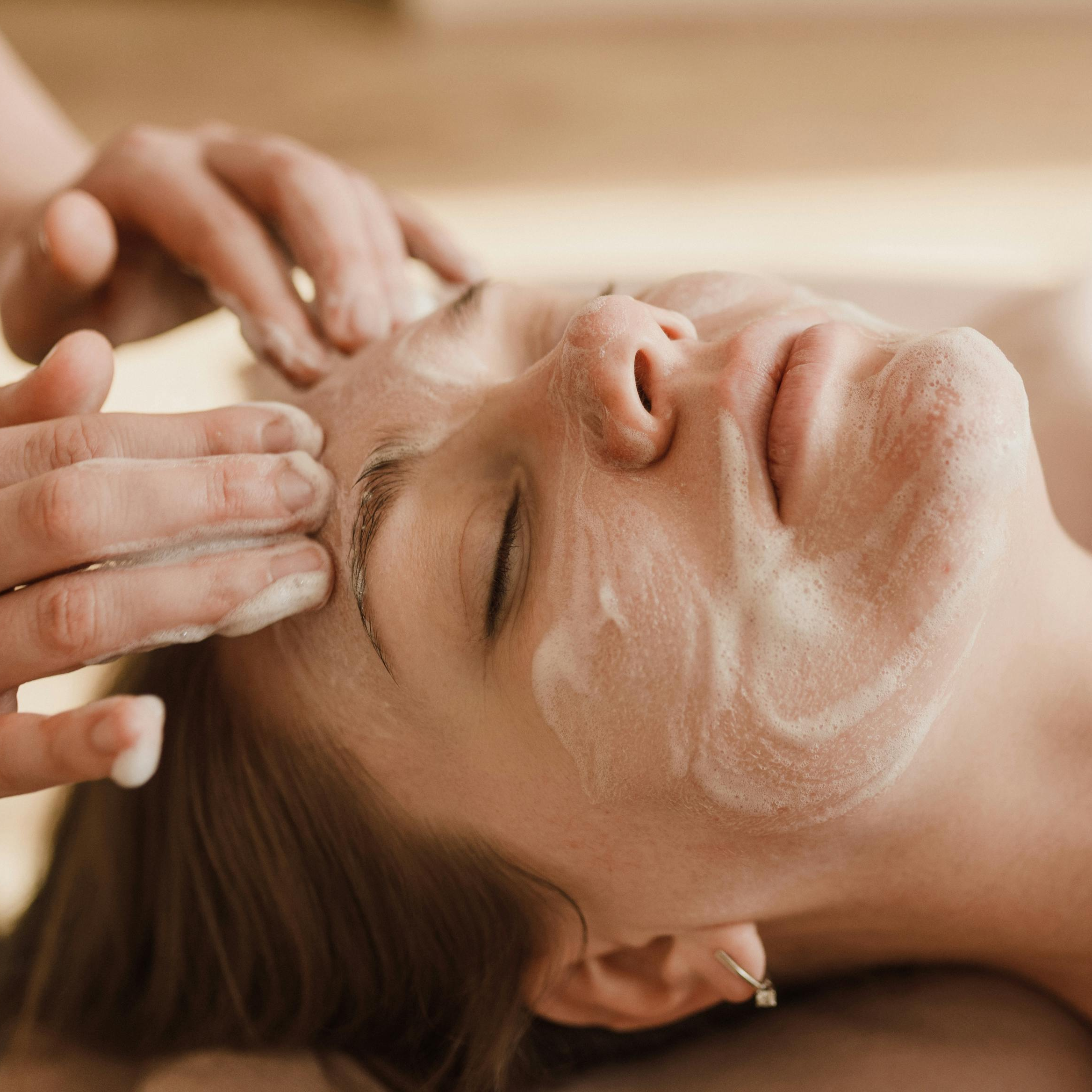 Person receiving a facial massage with cream on face